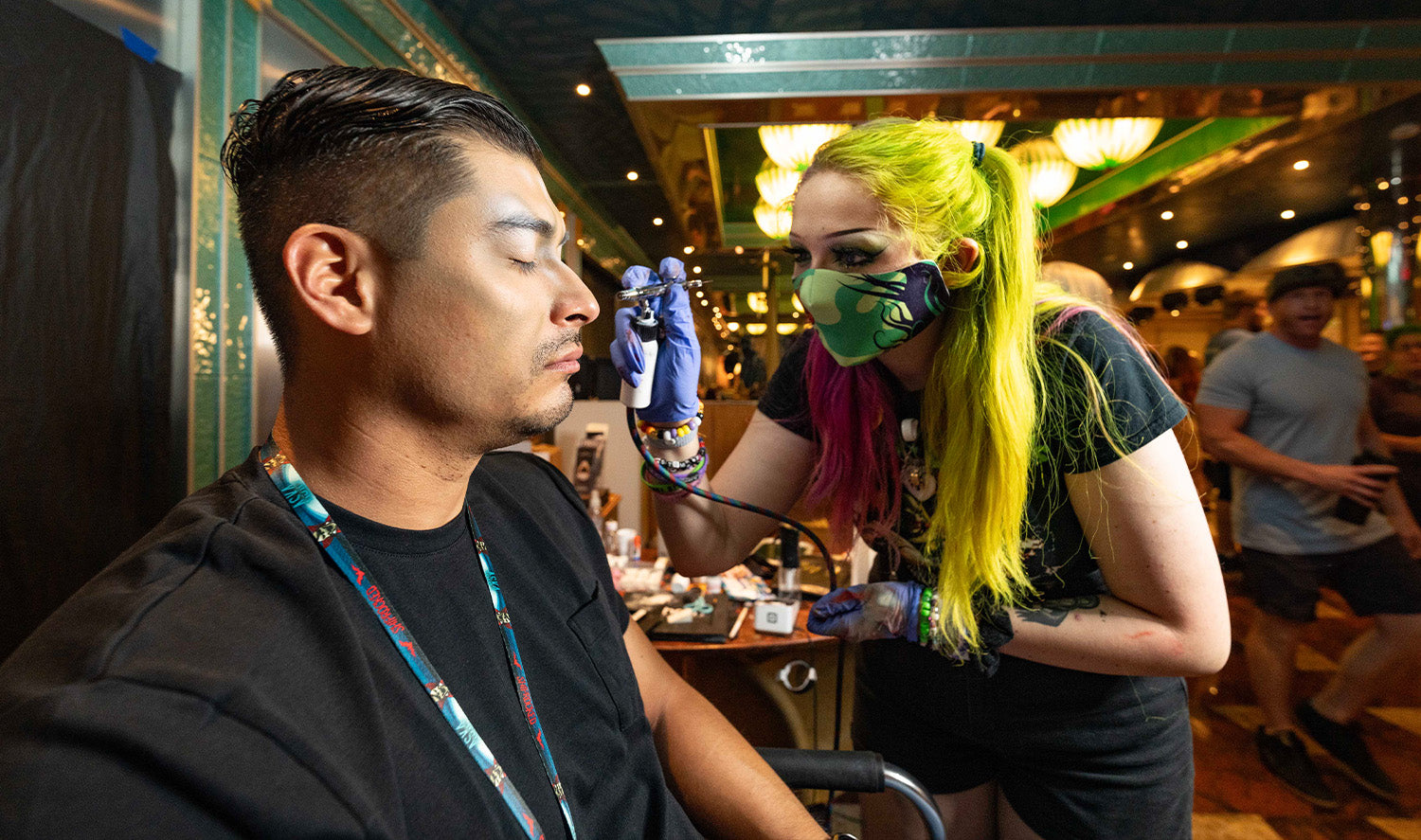 Artist applying air brush color to man's face