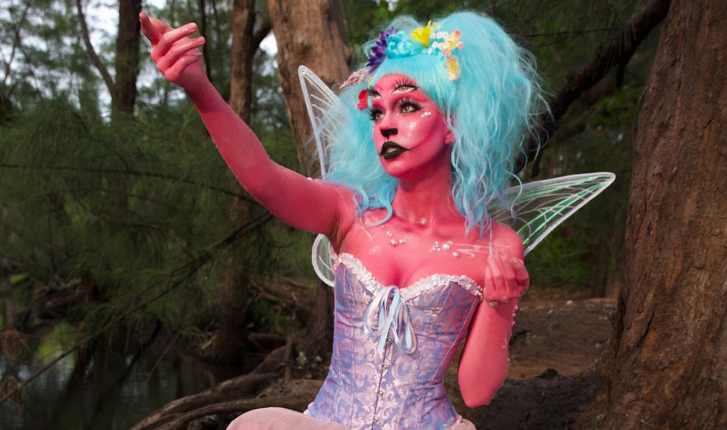 Woman with body painted in pink, light blue wig and wings